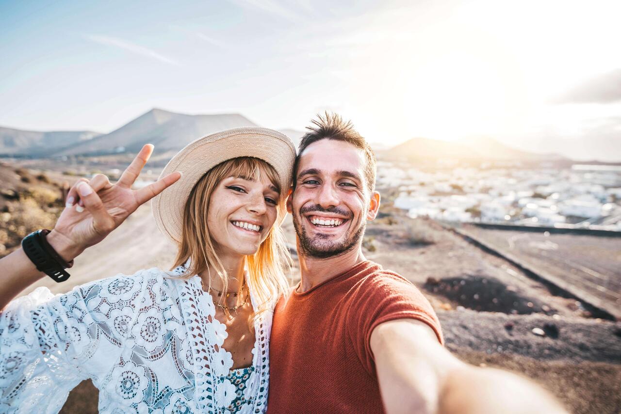 Flexibel an Bedürfnisse und die Lebenssituation anpassbar: Ein Pärchen nimmt ein Selfie von sich und der Naturlandschaft um sie herum auf und lacht in die Kamera.