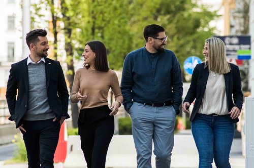 Bild von © Andi Bruckner: Vier ÖBV Außendienst-Mitarbeiter:innen aus dem Vertrieb gehen nebeneinander am Gehsteig entlang.