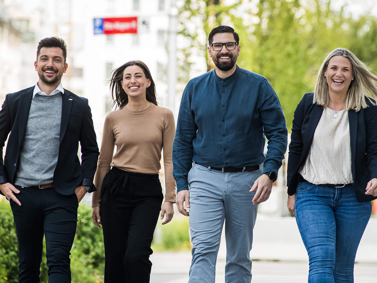 Bild von © Andi Bruckner: Vier Mitarbeiter:innen aus dem ÖBV Vertriebsaußendienst gehen nebeneinander am Gehsteig entlang.