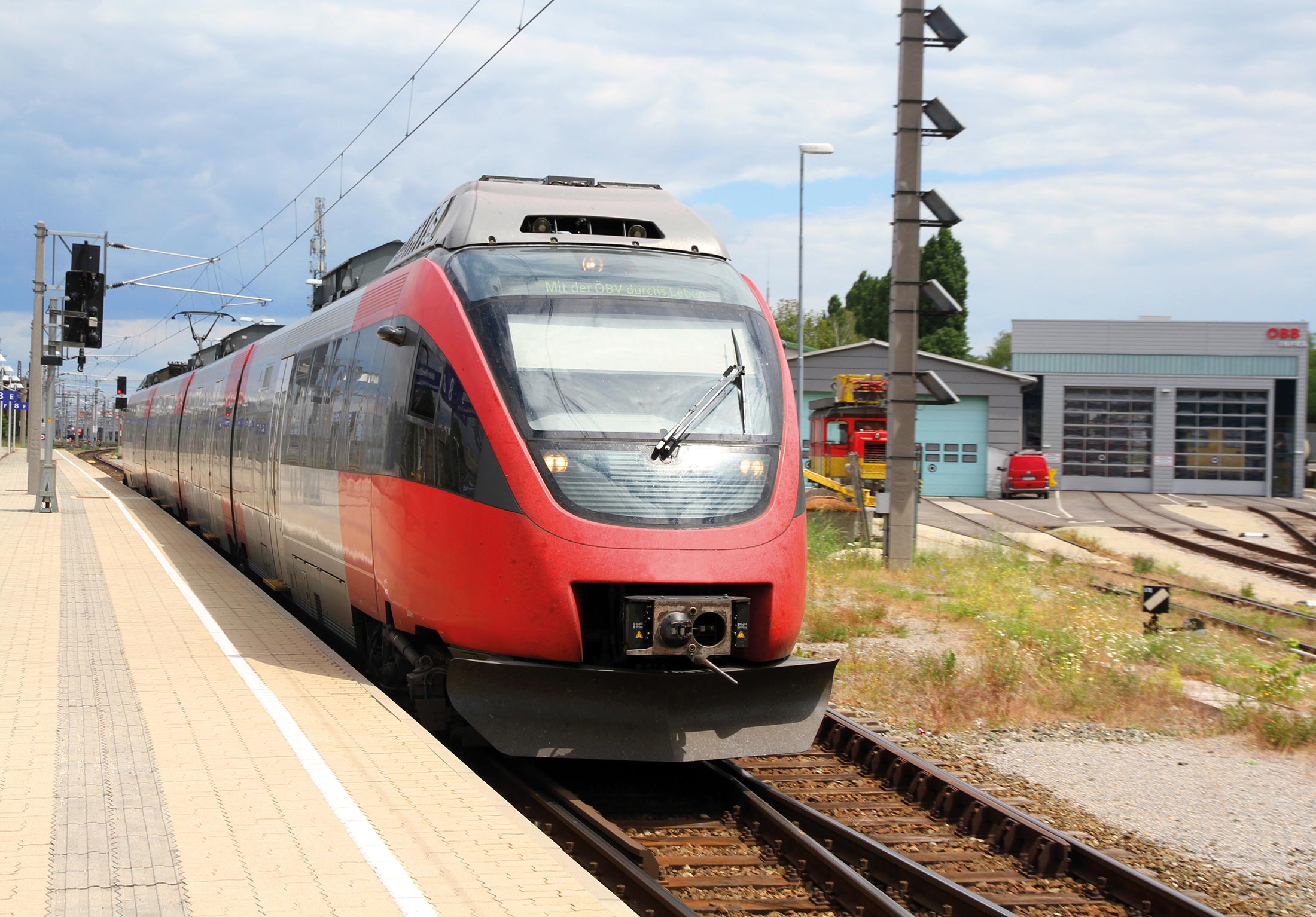 Einfahrender roter Zug am Bahnsteig